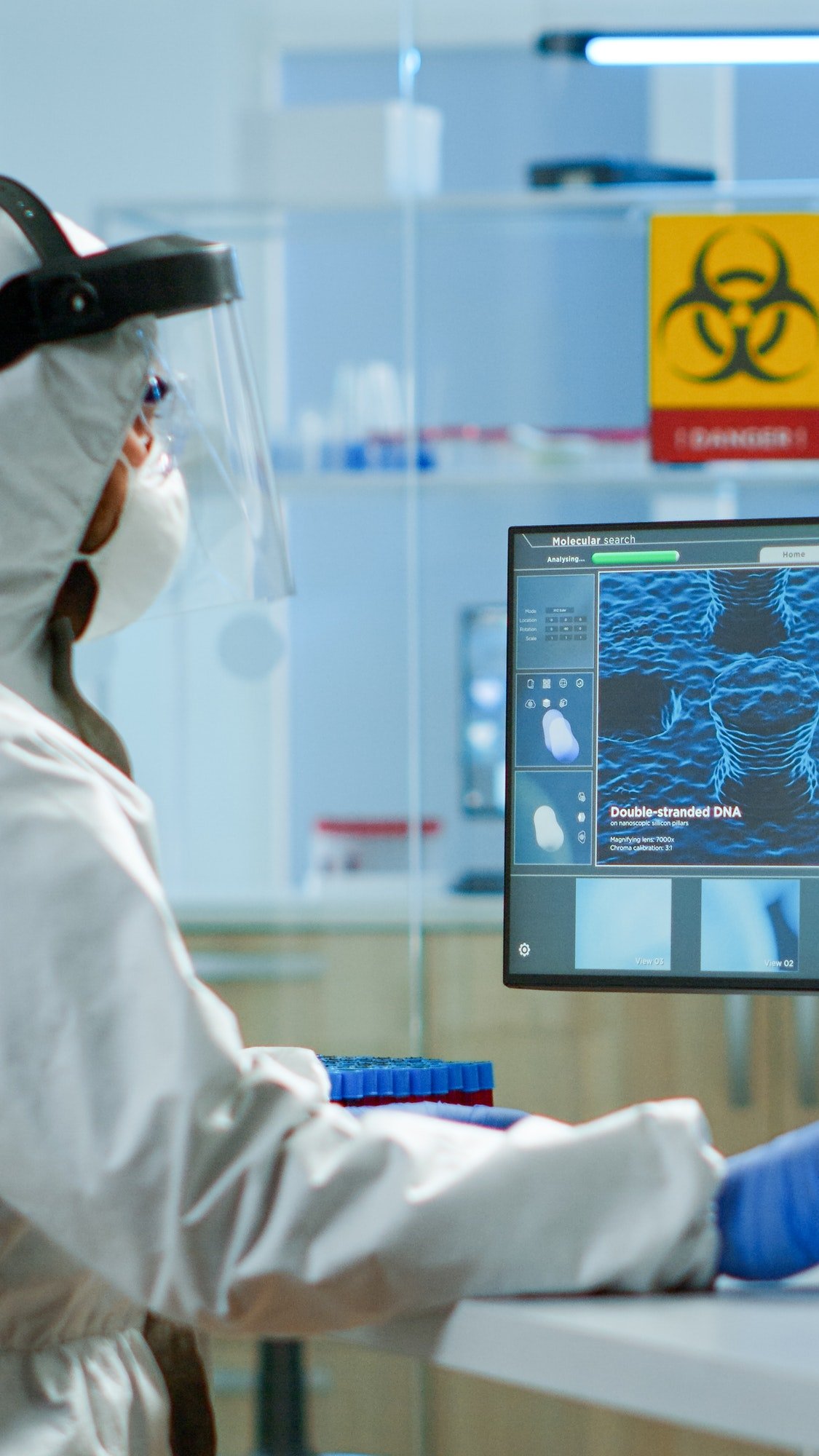 Man scientist working at vaccine development typing on pc in coverall